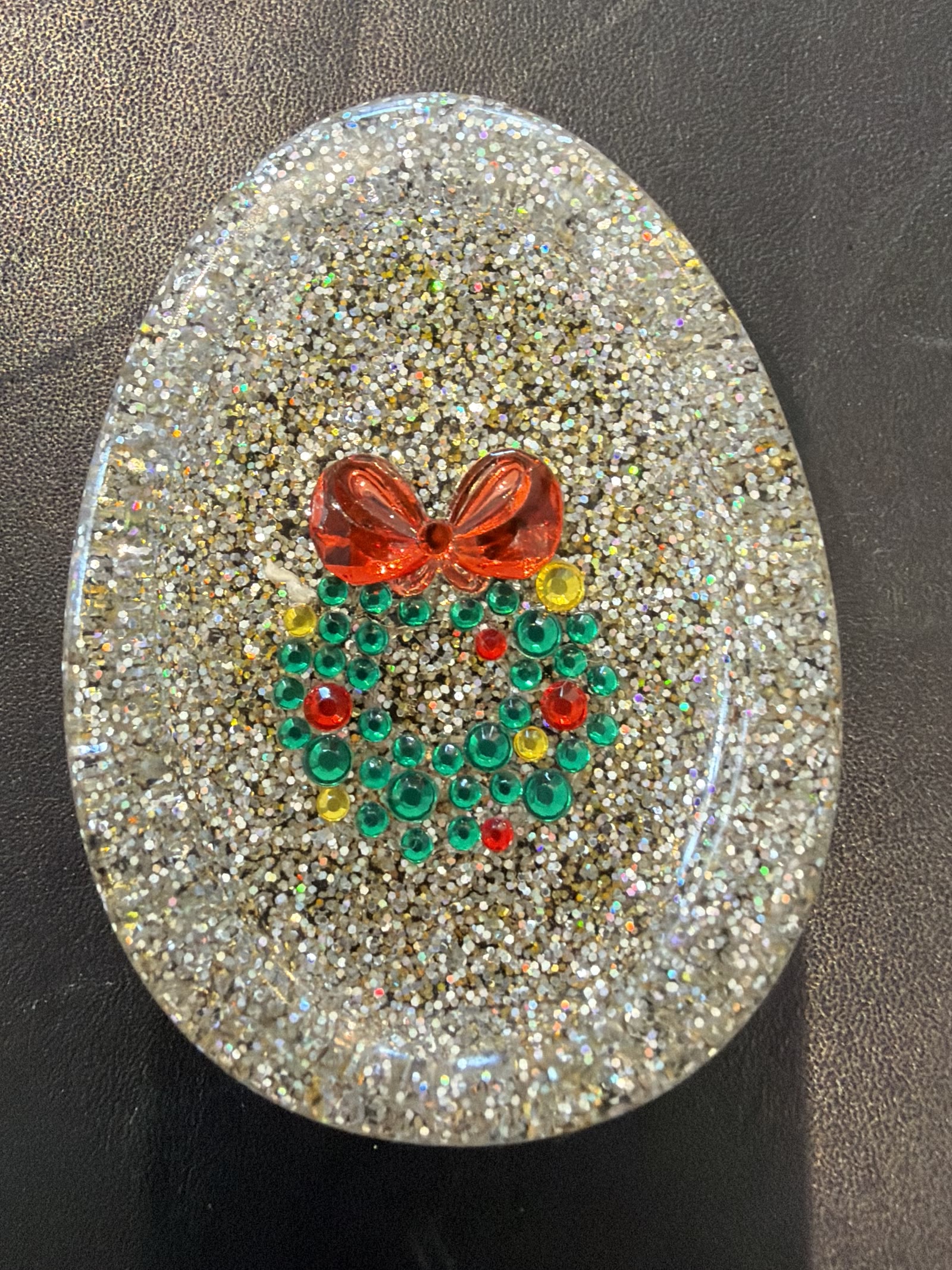Oval resin tray with silver and gold glitter and a Christmas wreath of green rhinestones topped with a red bow